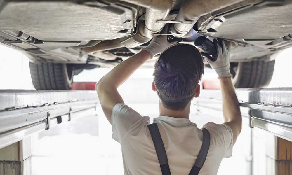 Technician inspecting the underside of a car